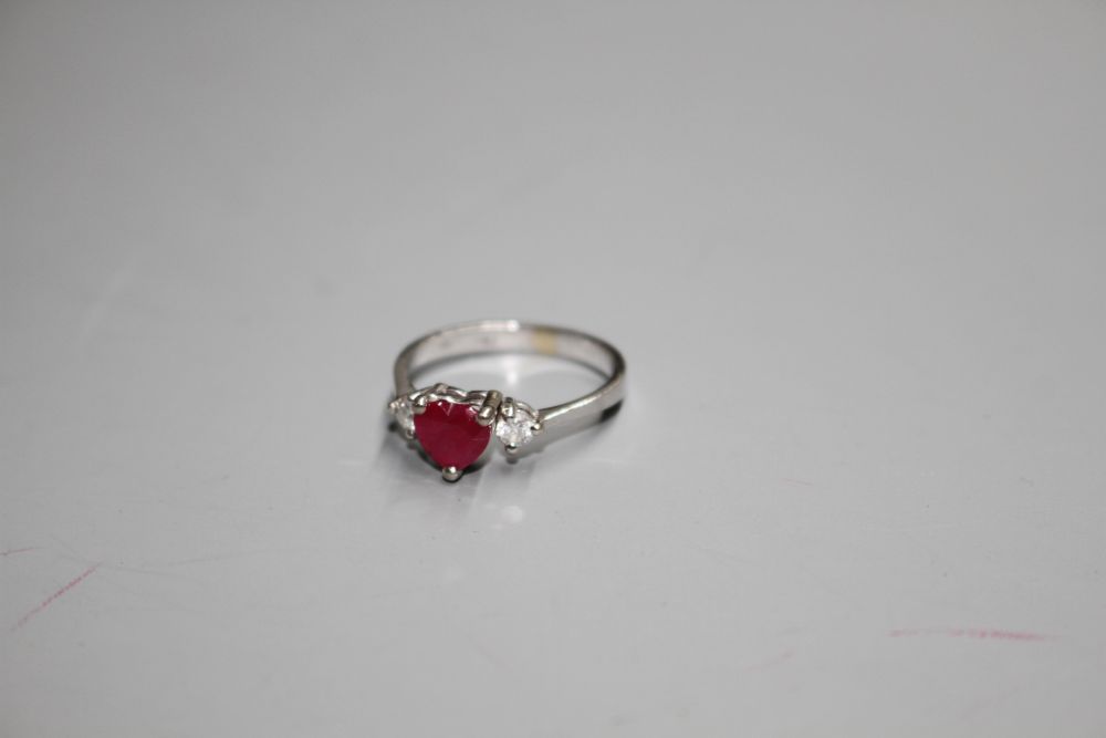 A modern 750 white metal, claw set heart shaped ruby and two round cut diamond set dress ring,